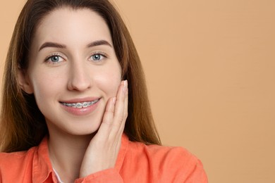 Photo of Portrait of smiling woman with dental braces on beige background. Space for text