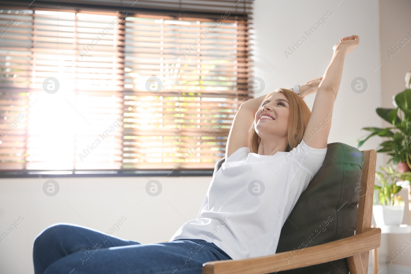 Photo of Young woman relaxing in armchair near window at home. Space for text