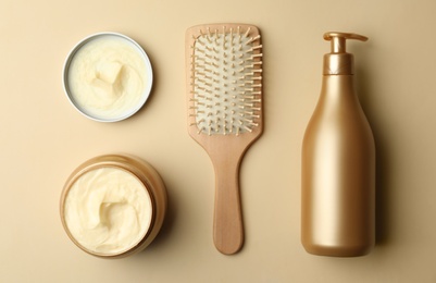 Hair cosmetic products and brush on beige background, flat lay