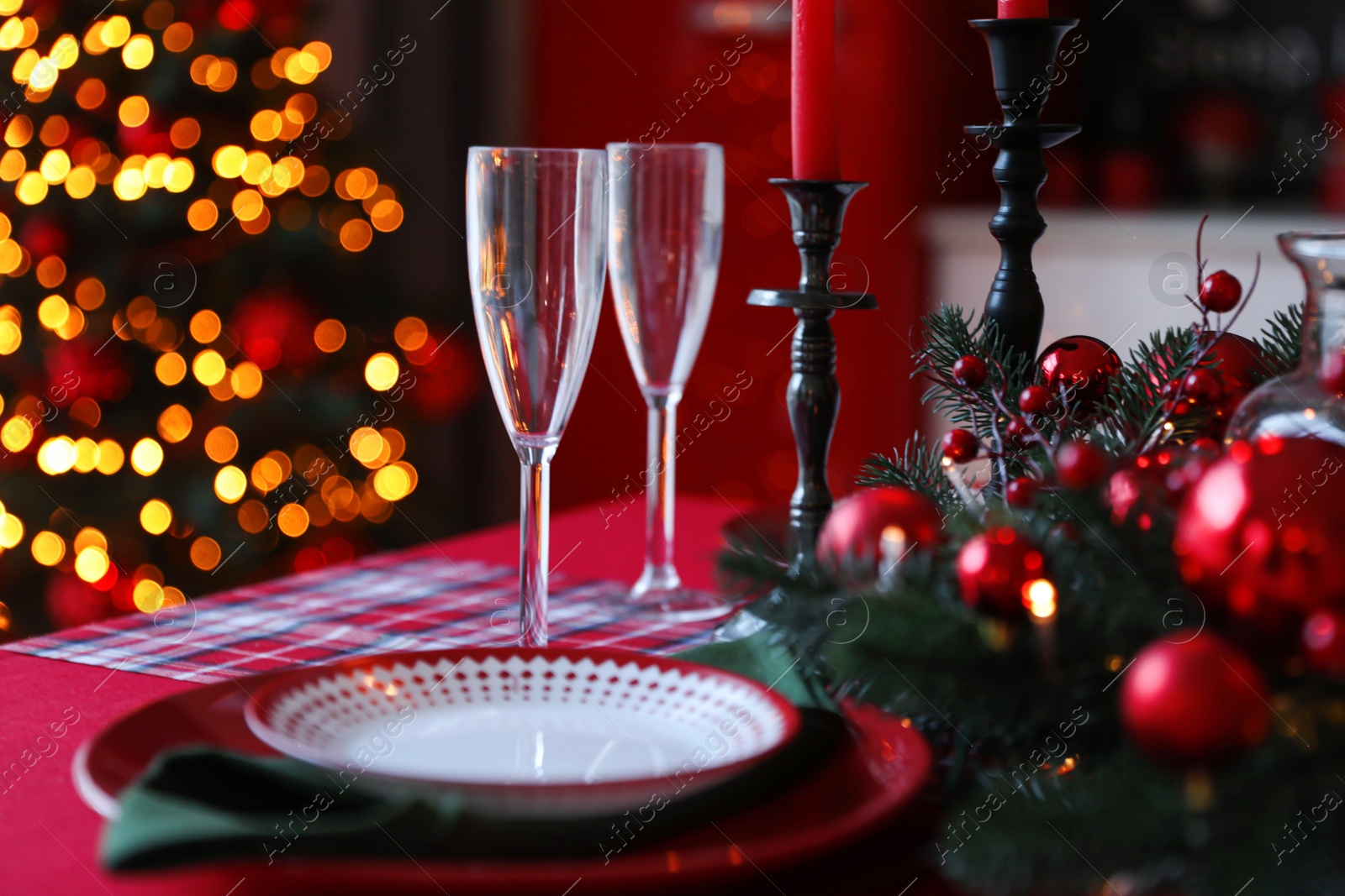 Photo of Table served for festive dinner and blurred Christmas tree in stylish kitchen interior, closeup