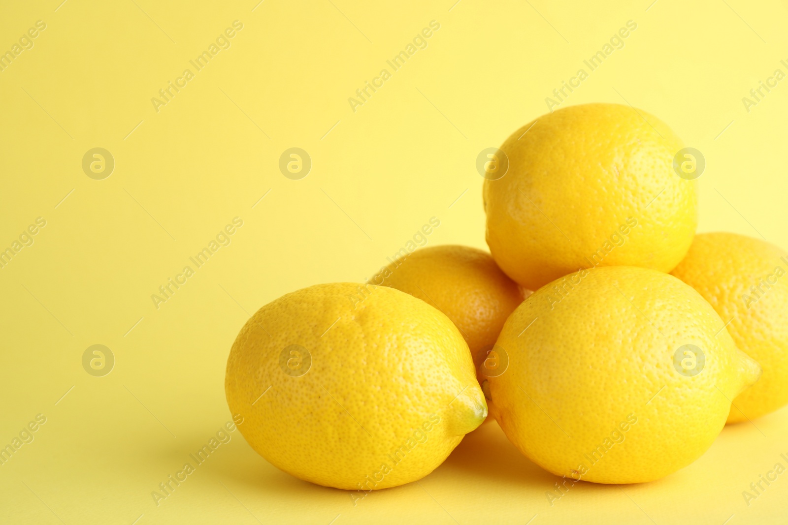 Photo of Fresh ripe lemons on yellow background. Space for text