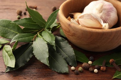 Aromatic fresh bay leaves and spices on wooden table, closeup