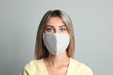 Photo of Young woman in protective face mask on light grey background