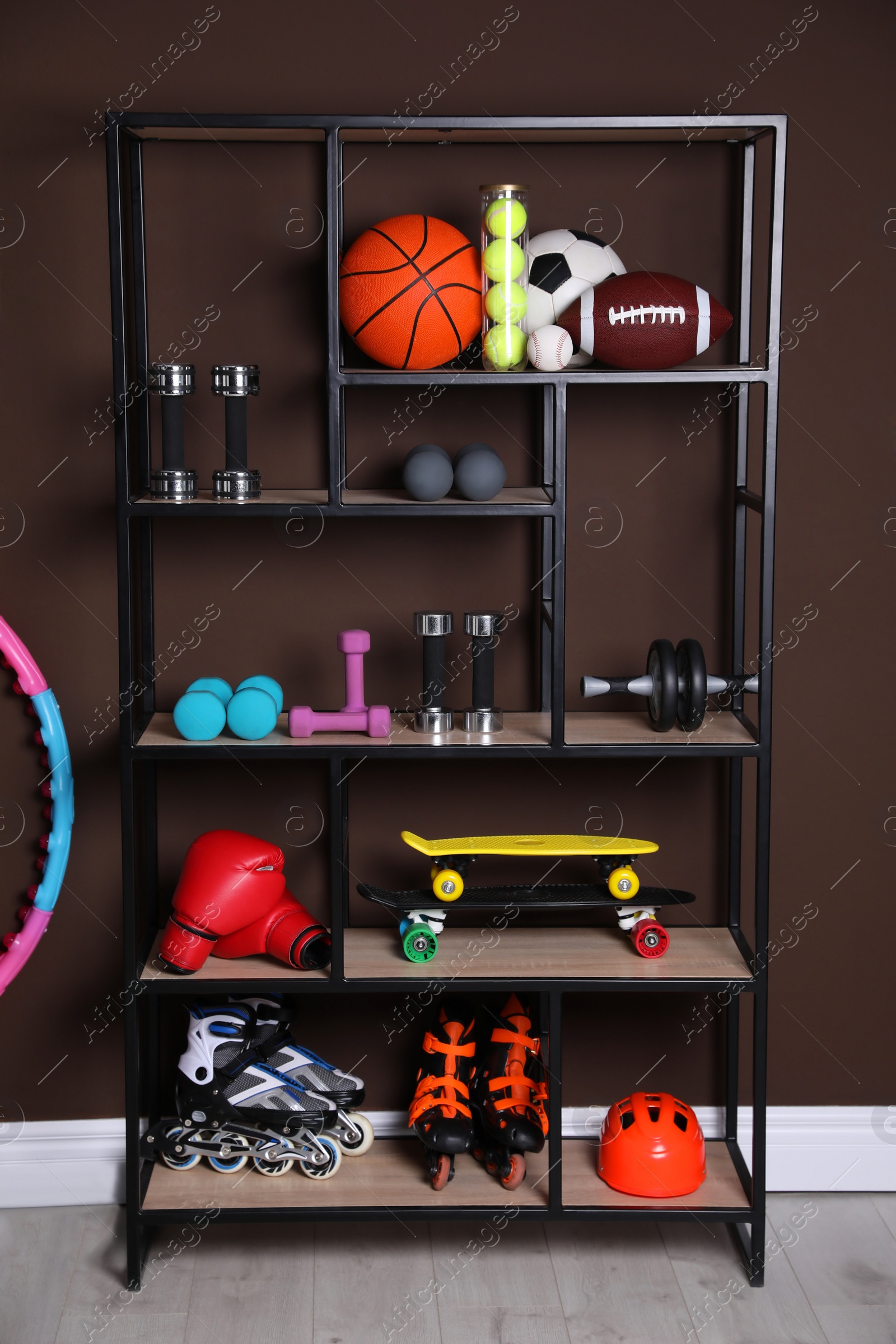 Photo of Shelving unit with different sports equipment near brown wall indoors