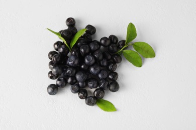 Photo of Pile of ripe bilberries and leaves on white background, flat lay