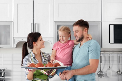 Beautiful woman treating her family with freshly oven baked buns in kitchen