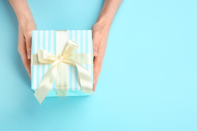 Photo of Young woman holding beautiful gift box on color background, top view