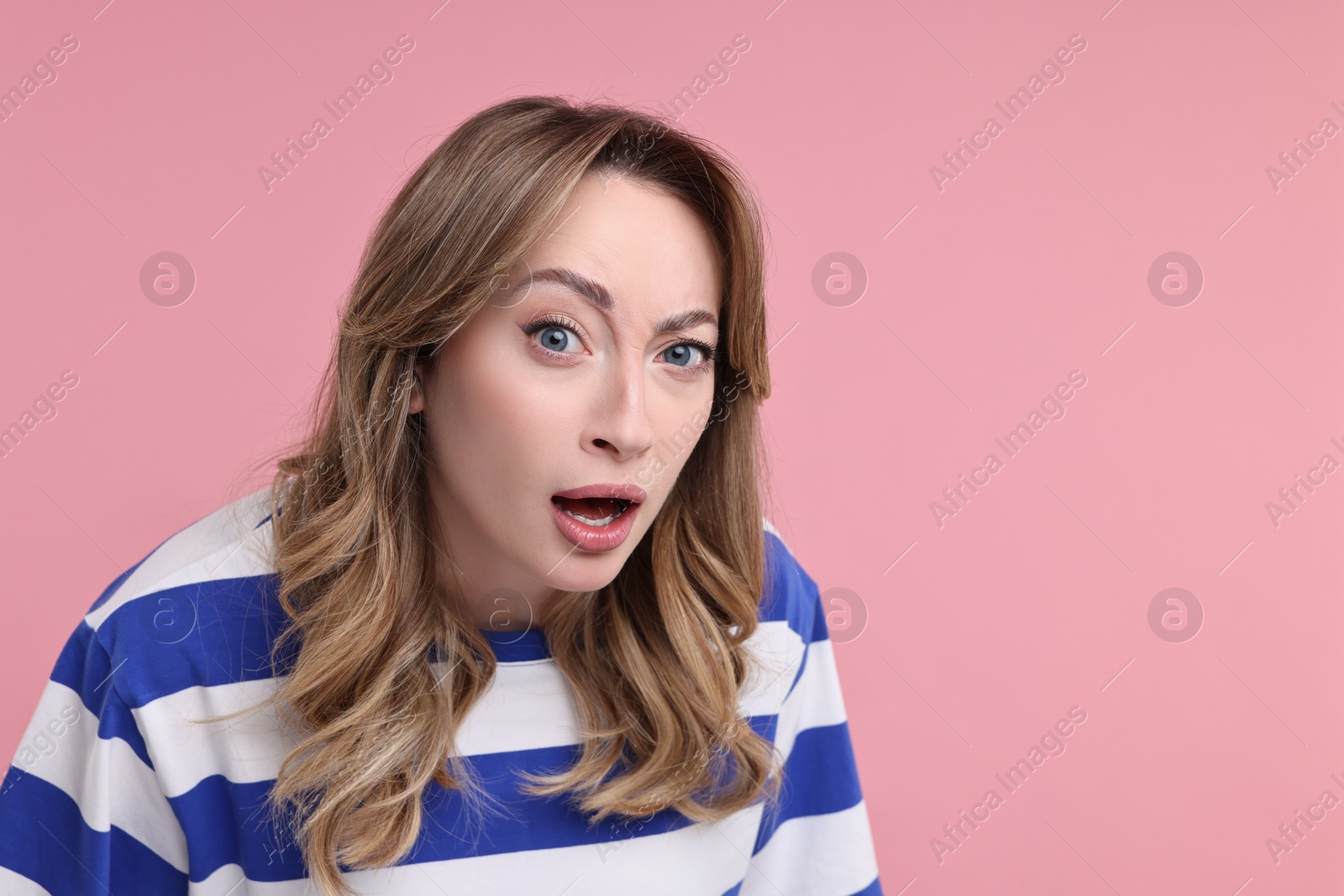 Photo of Portrait of surprised woman on pink background. Space for text