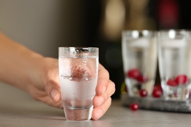 Woman with shot of vodka at table in bar, closeup