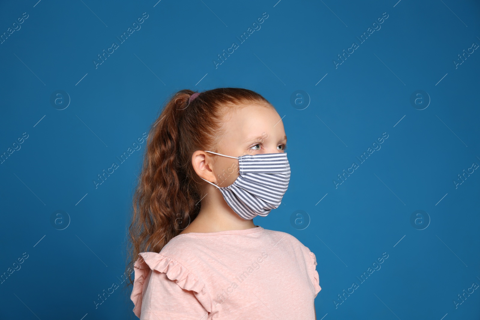 Photo of Preteen girl in protective face mask on blue background