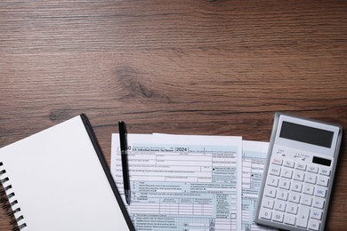 Payroll. Tax return forms, calculator, notebook and pen on wooden table, flat lay. Space for text