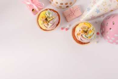 Photo of Cute sweet unicorn cupcakes and party hats on white background, flat lay. Space for text
