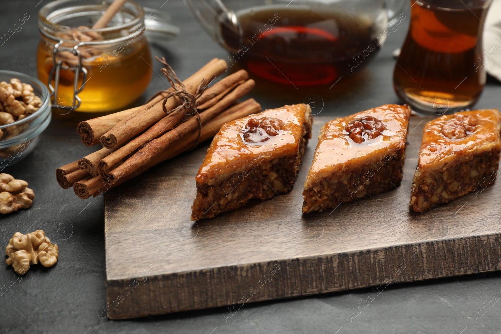 Photo of Delicious sweet baklava with walnuts and cinnamon on black table