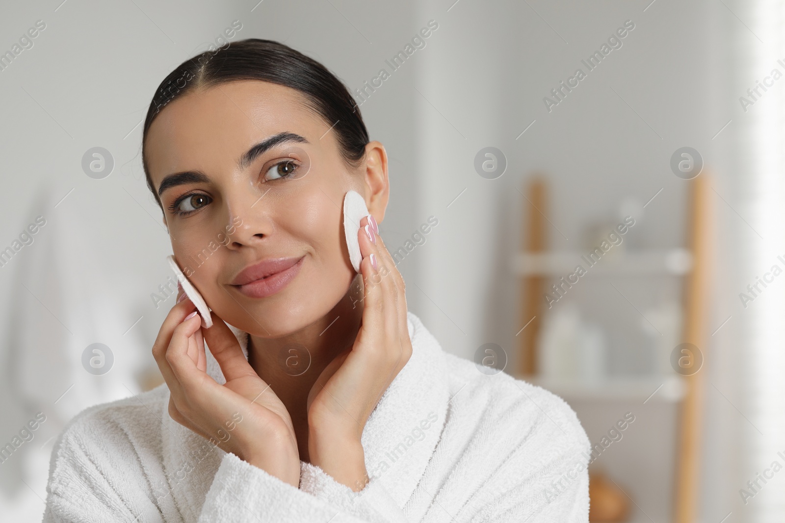 Photo of Beautiful woman removing makeup with cotton pads in bathroom. Space for text