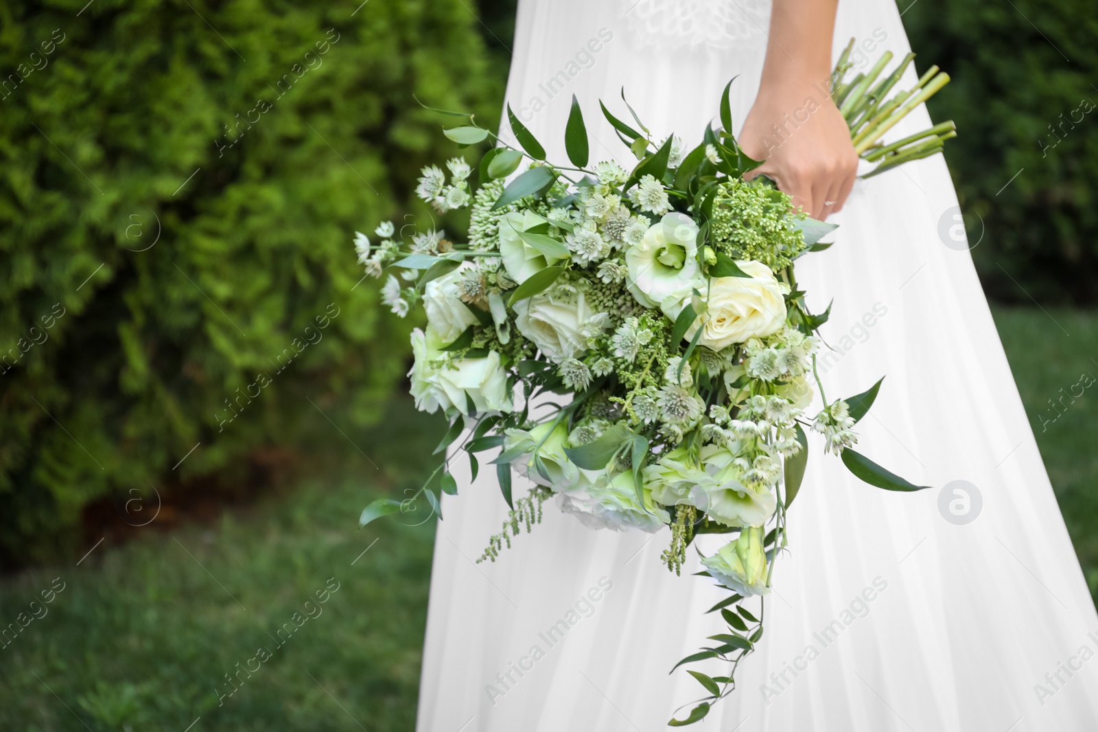 Photo of Bride in beautiful wedding dress with bouquet outdoors, closeup