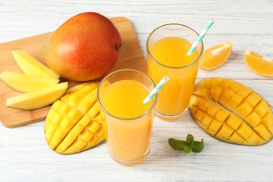 Tasty mango drink and fresh fruits on wooden table