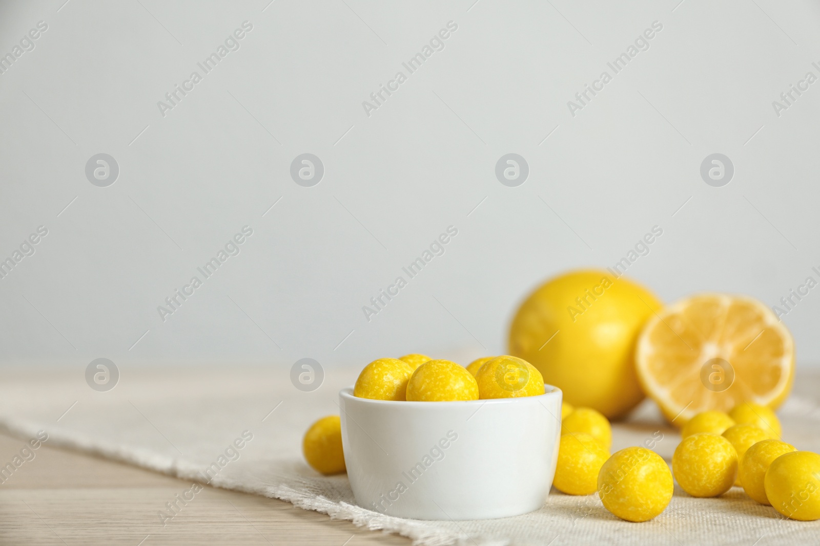 Photo of Tasty lemon drops on wooden table. Space for text