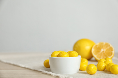 Photo of Tasty lemon drops on wooden table. Space for text