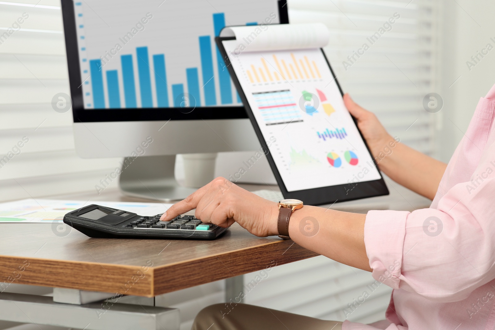 Photo of Accountant using calculator at wooden desk in office, closeup