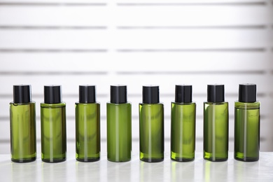 Row of mini bottles with cosmetic products on white table