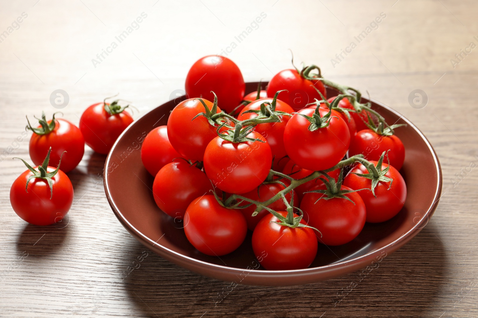 Photo of Plate with fresh cherry tomatoes on wooden background