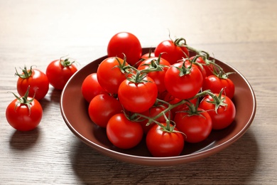 Plate with fresh cherry tomatoes on wooden background