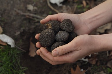 Photo of Woman holding fresh truffles in hands outdoors, closeup