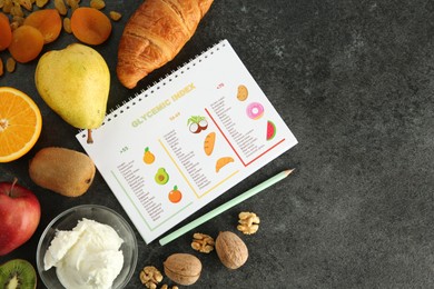 Photo of Notebook with glycemic index chart and products on grey table, flat lay. Space for text