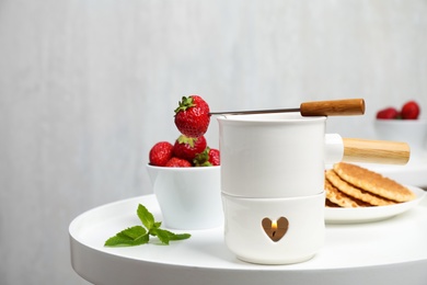 Photo of Fondue pot with chocolate and strawberry on white table