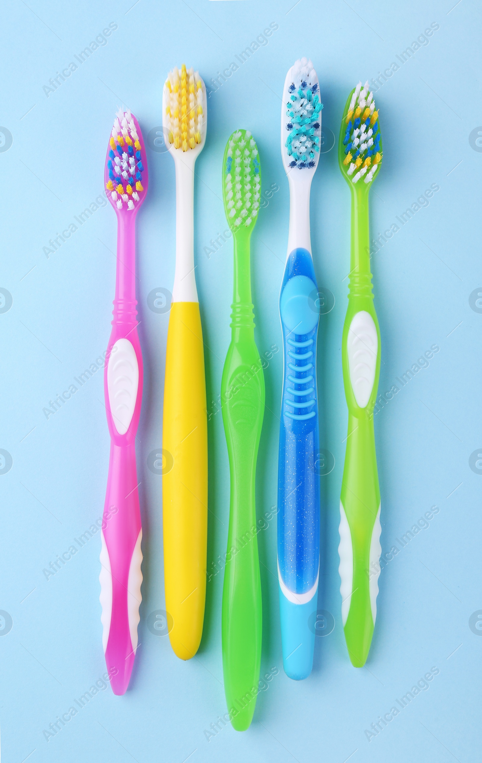 Photo of Many different toothbrushes on light blue background, flat lay