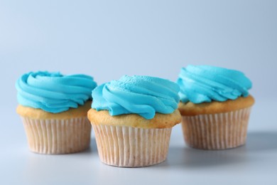 Photo of Delicious cupcakes with bright cream on light background