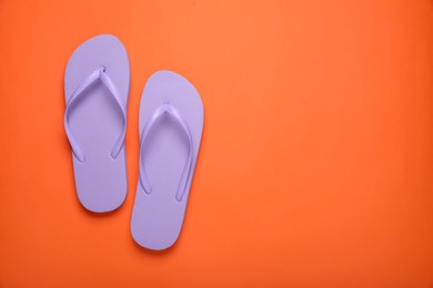 Photo of Stylish violet flip flops on orange background, top view. Space for text