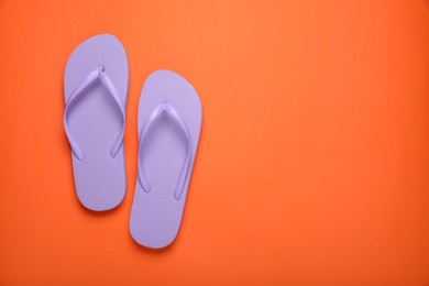 Stylish violet flip flops on orange background, top view. Space for text