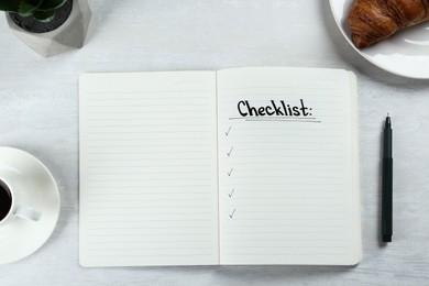 Notebook with inscription Checklist, cup of coffee and croissant on white wooden table, flat lay