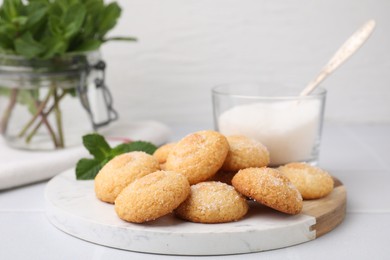 Photo of Tasty sweet sugar cookies, milk and mint on white tiled table, closeup