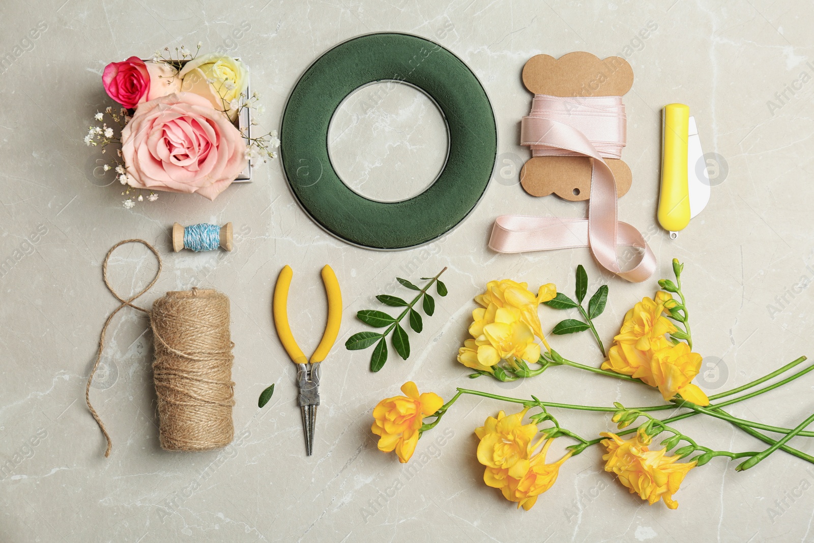 Photo of Florist equipment with flowers on light background, top view