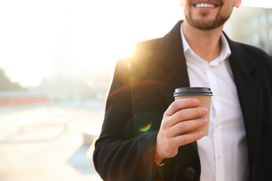 Man with cup of coffee on city street in morning, closeup