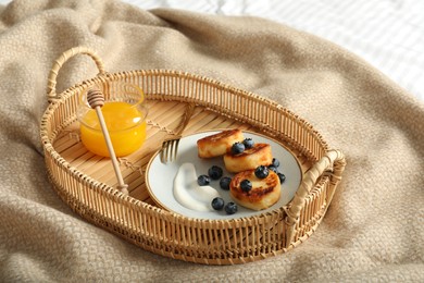 Photo of Delicious cottage cheese pancakes with fresh blueberries and sour cream served on bed tray