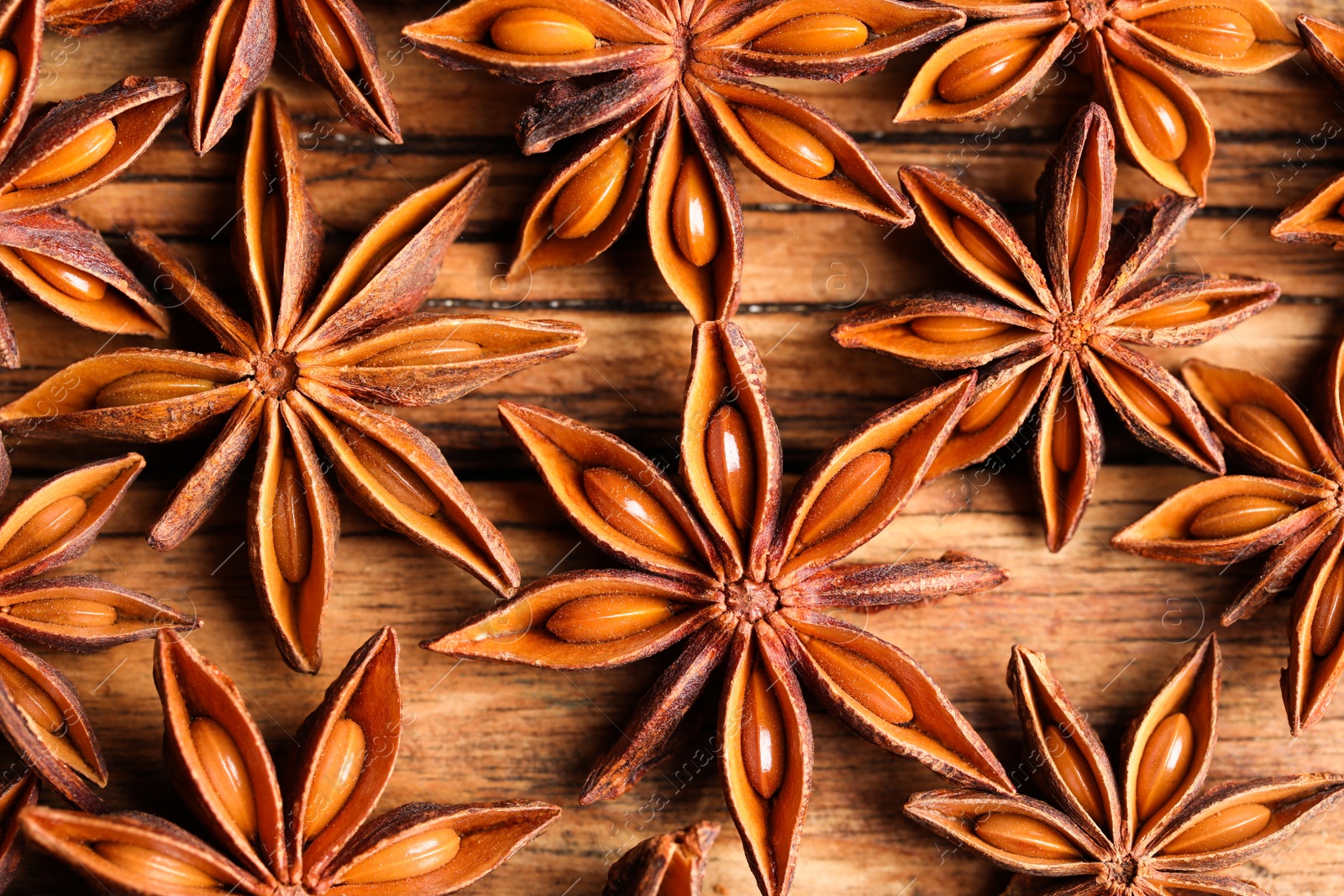 Photo of Aromatic anise stars on wooden table, flat lay