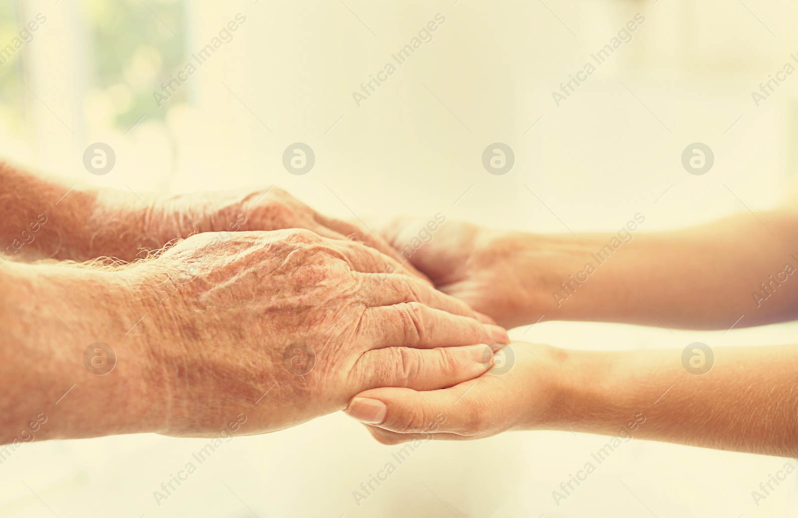 Image of Helping hands on blurred background, closeup. Elderly care concept