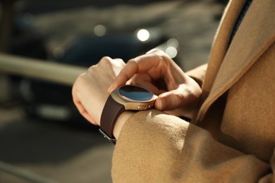 Photo of Mature woman using smart watch outdoors, closeup