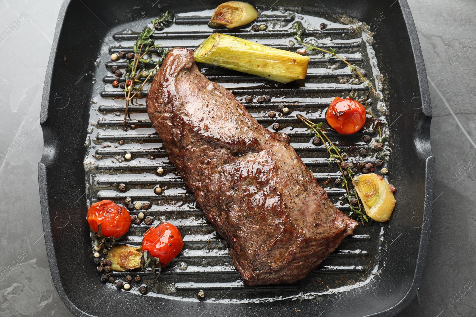 Photo of Delicious grilled beef meat and vegetables in pan on grey table, top view