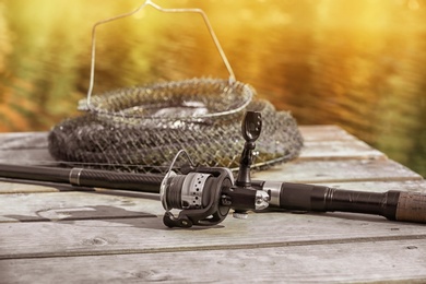 Photo of Fishing rod and fresh fish on wooden pier near pond