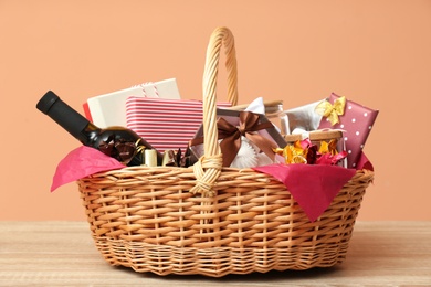 Wicker gift basket with bottle of wine on wooden table