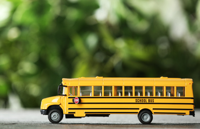 Photo of Yellow school bus on table against blurred background. Transport service