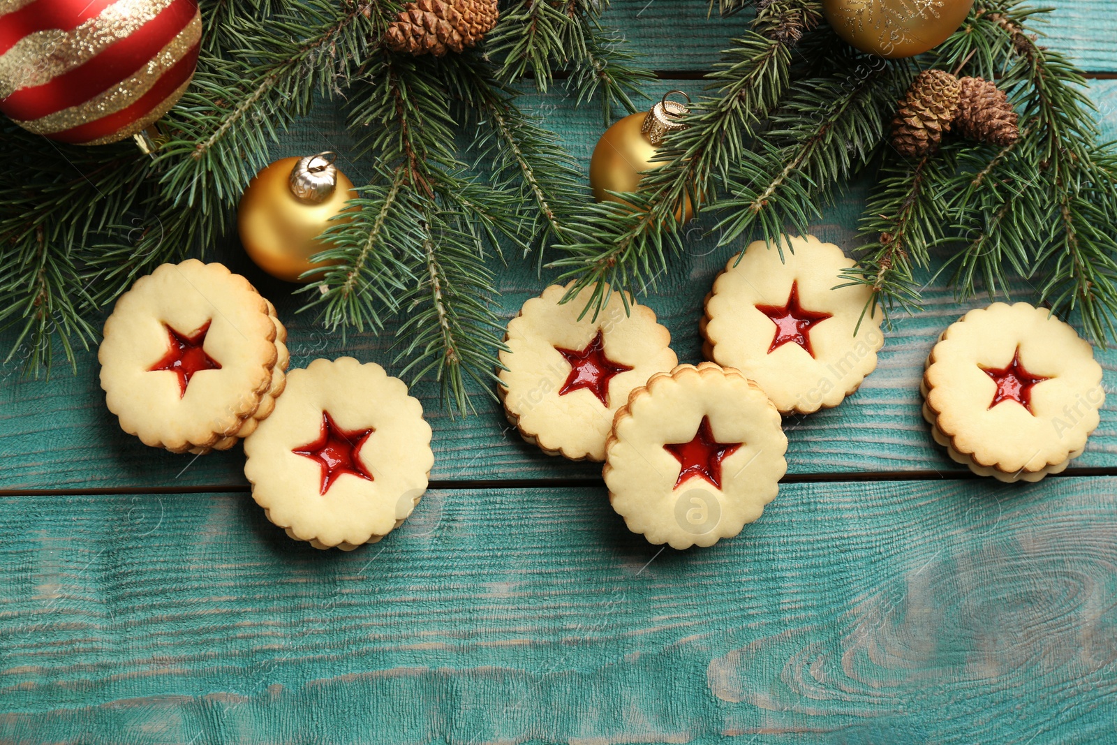 Photo of Linzer cookies with sweet jam and Christmas decorations on wooden background, top view