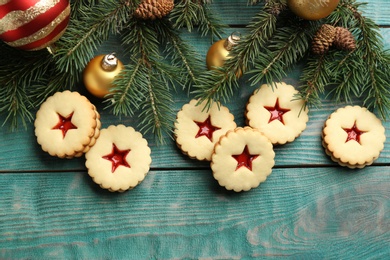 Photo of Linzer cookies with sweet jam and Christmas decorations on wooden background, top view
