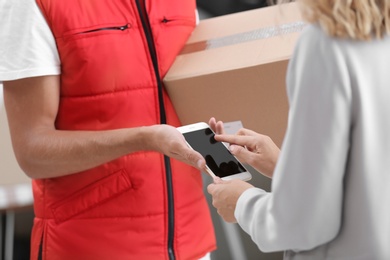 Woman using smartphone app to confirm receipt of parcel from courier, closeup
