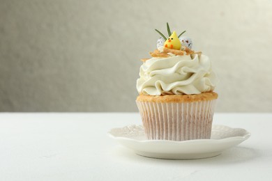 Tasty Easter cupcake with vanilla cream on white table, space for text