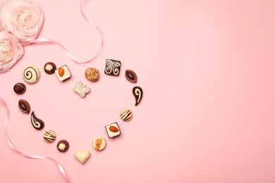 Photo of Heart made with delicious chocolate candies on light pink background, flat lay. Space for text